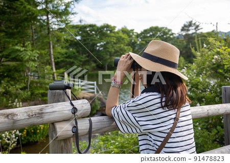 A woman bird watching on a plateau in the summer A woman bird watching on a plateau in the summer 91478823