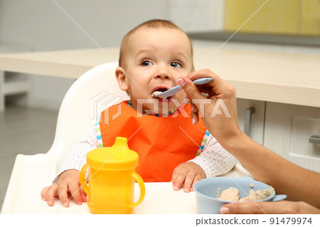 Young mother feeding her little baby at home Young mother feeding her little baby at home 91479974