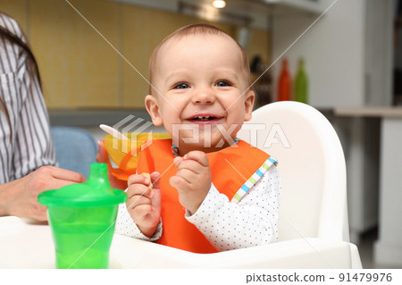 Young mother feeding her little baby at home Young mother feeding her little baby at home 91479976