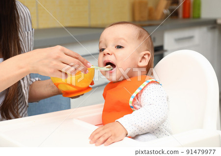 Young mother feeding her little baby at home Young mother feeding her little baby at home 91479977