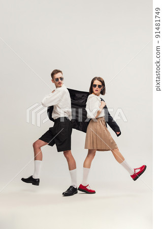 Full-length portrait of stylish young couple, man and woman in retro suit posing isolated over grey studio background 91481749