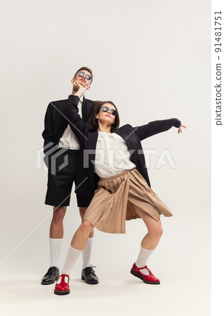 Full-length portrait of stylish young couple, man and woman in retro suit posing isolated over grey studio background. Party mood Full-length portrait of stylish young couple, man and woman in retro suit posing isolated over grey studio background. Party mood 91481751