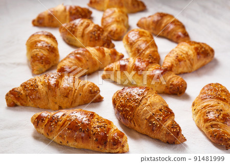 Lots of crispy ruddy croissants on a white background Lots of crispy ruddy croissants on a white background 91481999