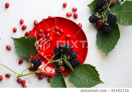 sweet Gumi berries and blackberries on a red plate, top view 91482118