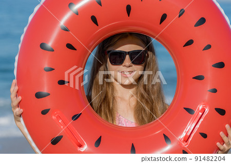 A teenage girl in glasses looks through an inflatable ring. A teenage girl in glasses looks through an inflatable ring. 91482204