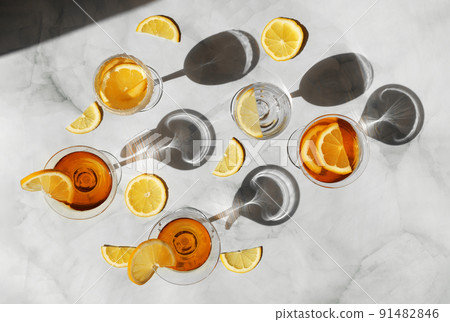 Summer cocktails in the sunlight. Fresh juicy beverages in glasses with shadows making trendy pattern. Delicious lemonade, cold tea, soda and water on gray marble background 91482846