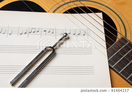 acoustic guitar tuning music sheets and tuning fork close up acoustic guitar tuning music sheets and tuning fork close up 91484157