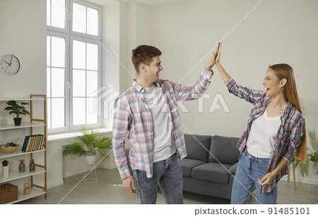 Happy, excited young couple celebrate buying new house and give each other high five 91485101