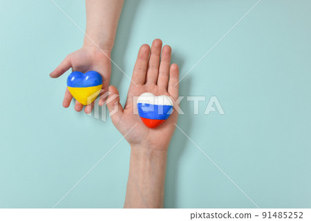 Children's hands hold a heart with the flags of the countries of Russia and Ukraine. 91485252