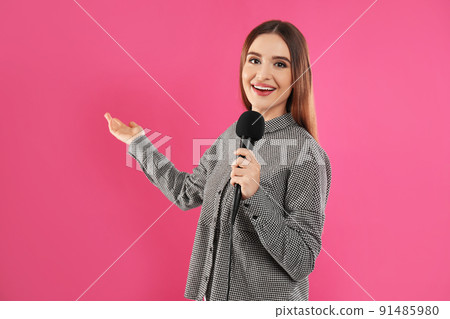 Young female journalist with microphone on pink background 91485980