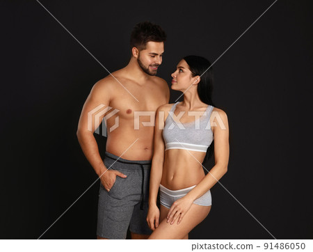 Young couple in grey sportive underwear on black background 91486050
