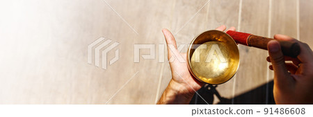 Man hands using singing bowl in sound healing therapy outdoors, closeup banner 91486608