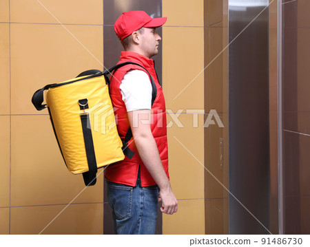 Male courier with thermo bag waiting for elevator. Food delivery service Male courier with thermo bag waiting for elevator. Food delivery service 91486730