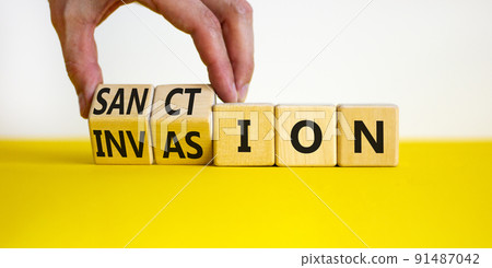 Sanction against invasion symbol. Businessman turns cubes and changes the concept word Invasion to Sanction. Beautiful white background. Business sanction against invasion concept. Copy space. 91487042