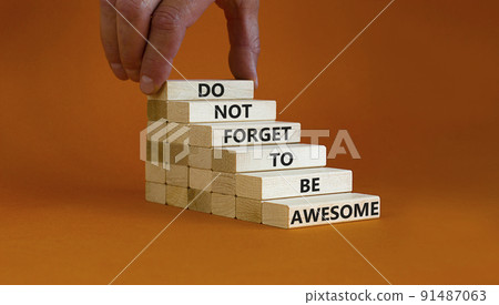 Do not forget to be awesome symbol. Concept words 'Do not forget to be awesome' on wooden blocks on a beautiful orange background. Businessman hand. Business, motivational, be awesome concept. 91487063