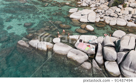 Lake Tahoe rocky shoreline. Ladies relaxing in the crystal clear water Lake Tahoe rocky shoreline. Ladies relaxing in the crystal clear water 91487494