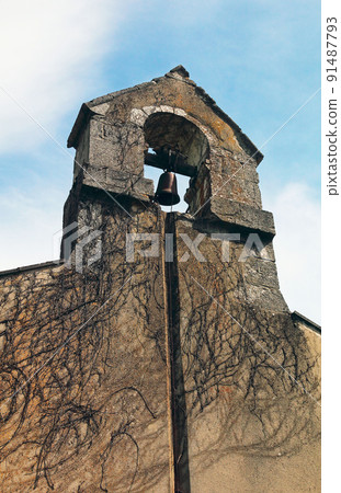 Old cemetery bell on the wall of the chapel covered with grape shoots. Old cemetery bell on the wall of the chapel covered with grape shoots. 91487793