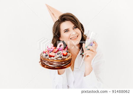 a lilt woman with a glass of champagne and a birthday cake with candles. 91488062