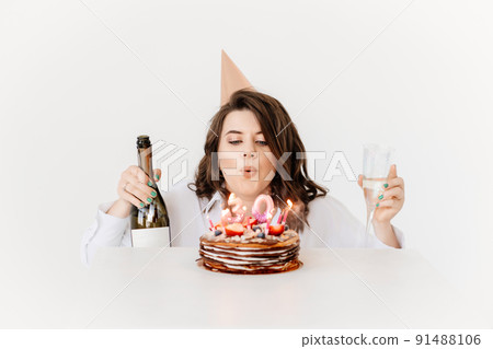 a happy woman with champagne and a birthday cake with candles. a happy woman with champagne and a birthday cake with candles. 91488106