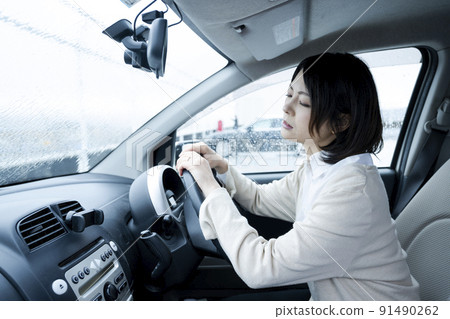 A woman holding her head in a car on a rainy day A woman holding her head in a car on a rainy day 91490262