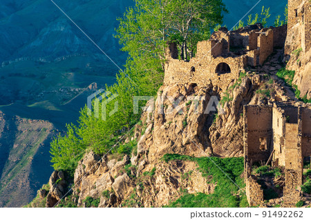 remains of stone houses on a sheer cliff in the abandoned village of Gamsutl in Dagestan 91492262