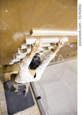 Bouldering image of a young man who trains his fingers with a camping board Bouldering image of a young man who trains his fingers with a camping board 91492602