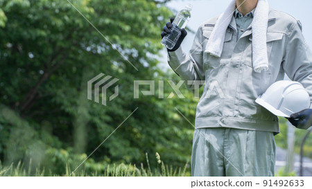 Men in work clothes drinking water from PET bottles | Image of measures against heat stroke in the construction industry 91492633