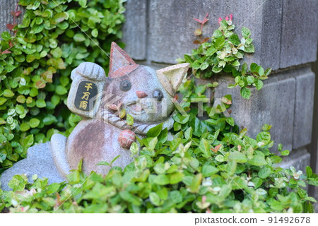 A statue of a beckoning cat with 10 million oval coins buried in a plant 91492678