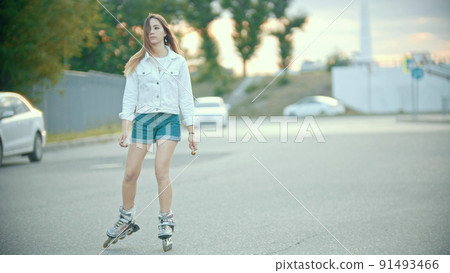 A shy teenage girl in rollerblades skating on the road A shy teenage girl in rollerblades skating on the road 91493466
