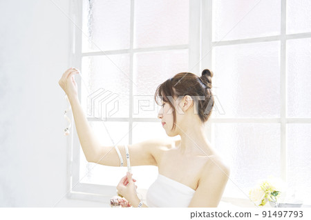 A woman measuring her upper arm with a tape measure in the living room 91497793