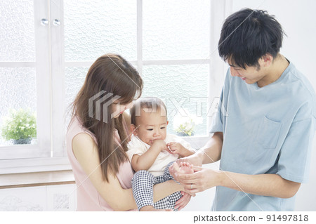 A couple playing with a baby in the living room A couple playing with a baby in the living room 91497818