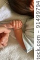 A baby who squeezes his mother's fingers while sleeping 91499794
