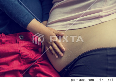 Child holding its mothers pregnant belly Child holding its mothers pregnant belly 91500351