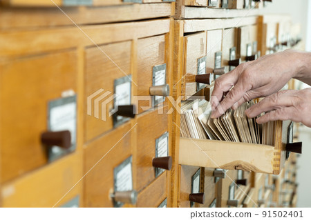 A male hand searching cards in old card catalogue. Man searching file A male hand searching cards in old card catalogue. Man searching file 91502401