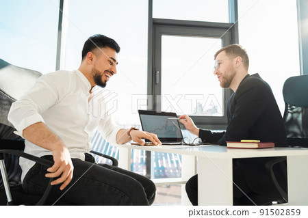 Two laughing businessmen in the office at the laptop analyze the growth of the company Two laughing businessmen in the office at the laptop analyze the growth of the company 91502859