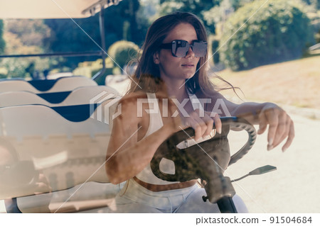 A middle-aged woman is driving a car for transporting tourists. Electric car, Tourist bus. Car for transporting people around the hotel, park, golf club A middle-aged woman is driving a car for transporting tourists. Electric car, Tourist bus. Car for transporting people around the hotel, park, golf club 91504684