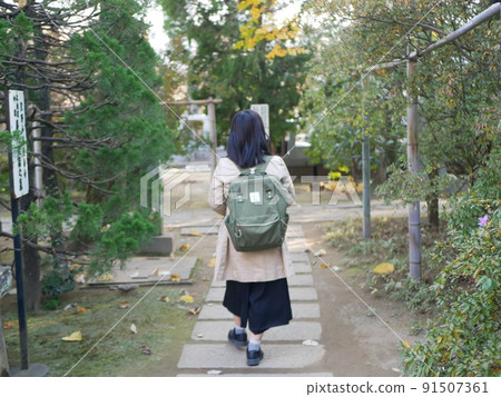 一個背著綠色背包走路的女人 91507361