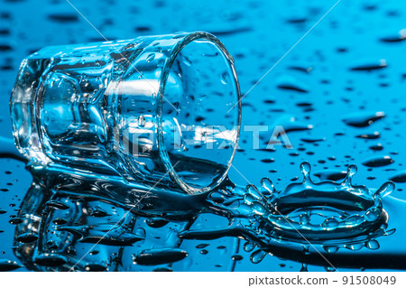 Glass lying on the side among the drops of spilled water Glass lying on the side among the drops of spilled water 91508049