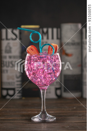 A glass with a pink cocktail filled with ice on dark background A glass with a pink cocktail filled with ice on dark background 91508055