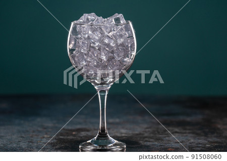 Glass full of ice standing on a table in the dark Glass full of ice standing on a table in the dark 91508060