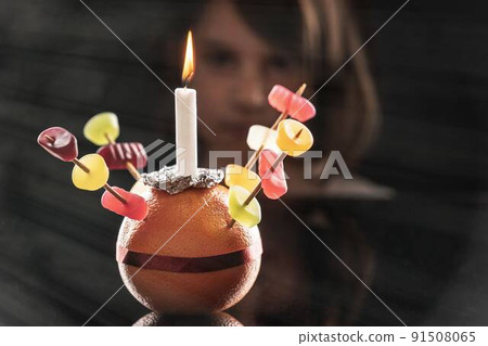 A little girl looks at the Orange Christingle she made. Selective focus. 91508065