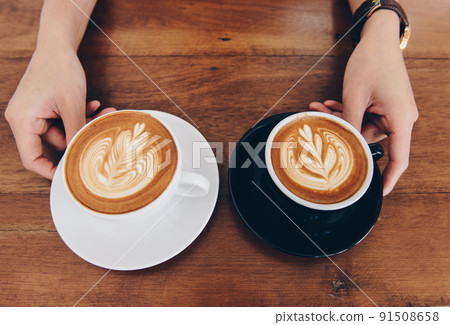 View of couple cup of hot latte coffee with hot cappuccino coffee serving on the wooden table. View of couple cup of hot latte coffee with hot cappuccino coffee serving on the wooden table. 91508658