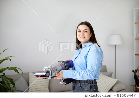Woman cleaning sofa with a modern cordless vacuum cleaner with a special nozzle, close-up. Dry cleaning concept with wireless vacuum cleanerWoman cleaning couch with vacuum cleaner at home Woman cleaning sofa with a modern cordless vacuum cleaner with a special nozzle, close-up. Dry cleaning concept with wireless vacuum cleanerWoman cleaning couch with vacuum cleaner at home 91509447