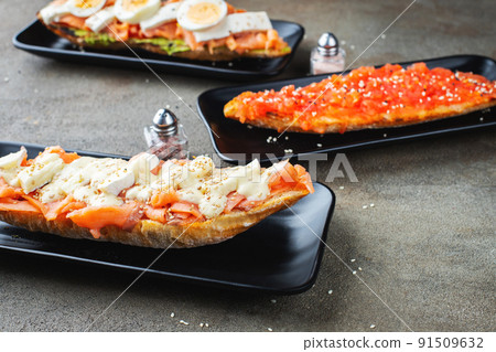 Traditional Spanish breakfast. Tostada with different toppings on a dark background 91509632