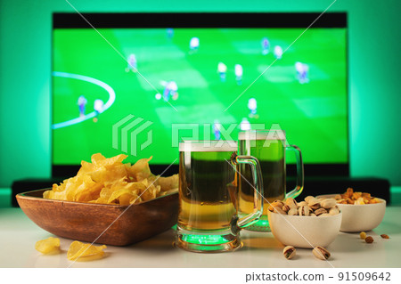 Beer and snacks set on football match tv background Beer and snacks set on football match tv background 91509642