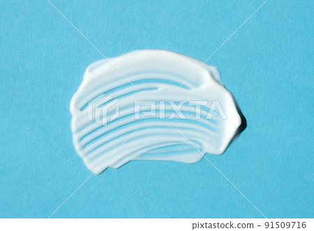 The texture of white cream on blue background. A smear of moisturizer closeup. Lotion swatch. Beauty, skin care product smear smudge drop. SPF sunscreen cream sample The texture of white cream on blue background. A smear of moisturizer closeup. Lotion swatch. Beauty, skin care product smear smudge drop. SPF sunscreen cream sample 91509716