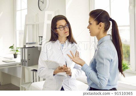 Young Caucasian woman in nurse coat works as doctor in cosmetology clinic listens to female patient 91510365
