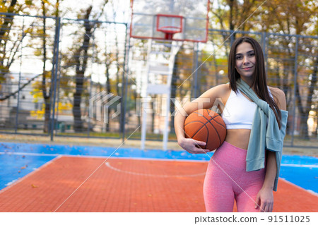 Athletic girl with a ball on basketball court Athletic girl with a ball on basketball court 91511025