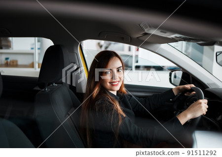 Pretty woman is testing a car while sitting in a salon at the dealer center. Pretty woman is testing a car while sitting in a salon at the dealer center. 91511292