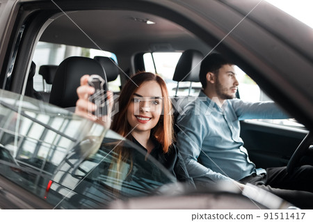 Young couple sitting in a car dealership inside their new car. Young couple sitting in a car dealership inside their new car. 91511417